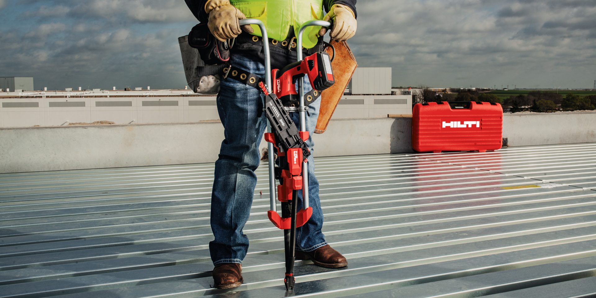 Operator on the metal deck using the Hilti screw fastening system (SDT Stand-up handle) to fasten down the deck